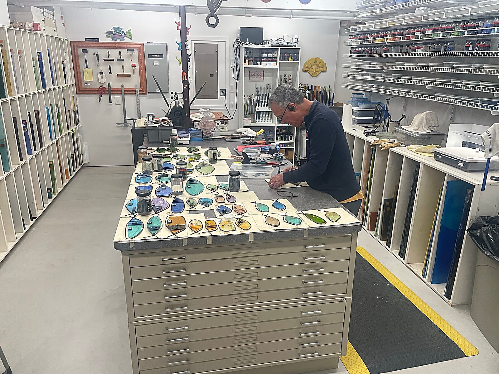 Jerry Harty working at a flat-file cabinet in his glass studio