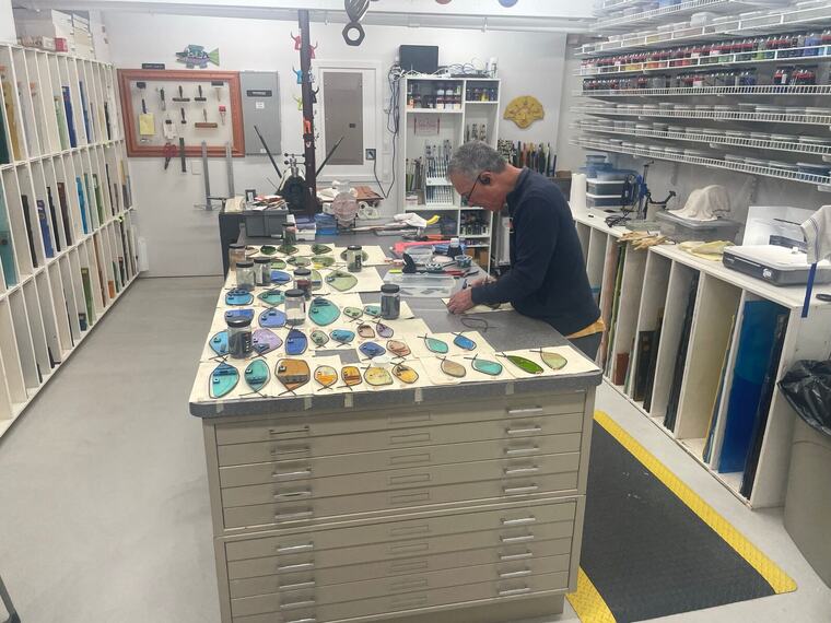 Jerry Harty working at a flat-file cabinet in his glass studio